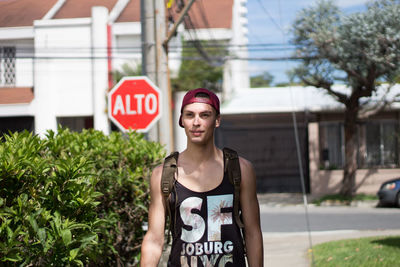 Young man walking on sidewalk against house