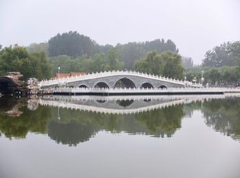 Bridge over river in city against clear sky