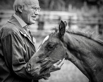 Senior man with horse standing outdoors