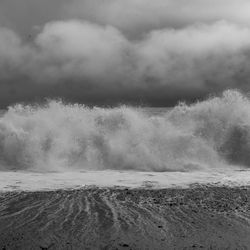 Waves splashing on shore against sky