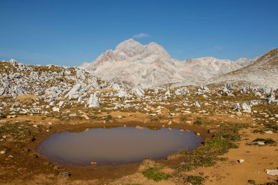 Scenic view of lake and mountains against blue sky