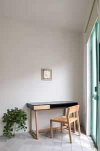 Wooden desk with chair, plants in the room, natural sunlight coming in, pasta tile