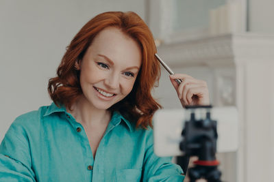 Smiling woman podcasting on smart phone at table