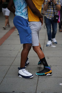 Low section of two young sportive african american gay males dancing in street, lgbt pride in usa