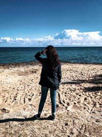Rear view of man standing on beach against sky