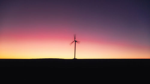 Wind turbines on landscape at sunset