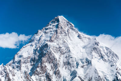 Low angle view of snowcapped mountains against blue sky