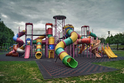 Slides on playground against cloudy sky at park