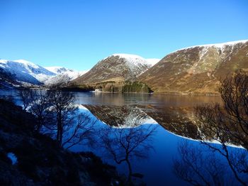 Scenic view of lake by snowcapped mountains against sky