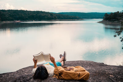 Woman sitting on rock by lake