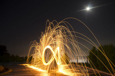 Illuminated wire wool at night against sky