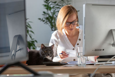 Businesswoman with cat on desk working in office