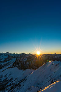 Scenic view of snowcapped mountains against blue sky