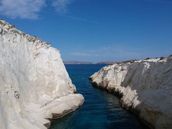 Rock formations by sea against blue sky