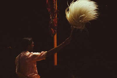 Rear view of man holding woman standing against black background