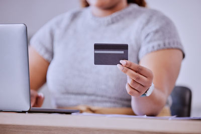 Midsection of woman using digital tablet at table