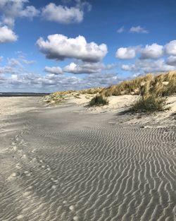 Sand dune on beach against sky
