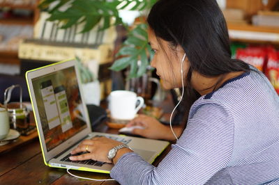 Side view of mid adult woman using laptop on table