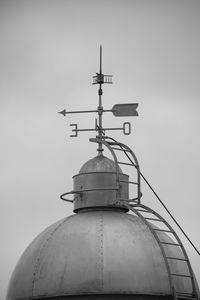 Low angle view of weather vane against building