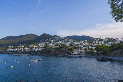 Scenic view of sea by townscape against sky