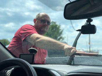 Mature man cleaning car windshield