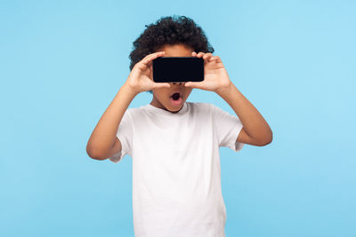 Man holding camera while standing against blue background