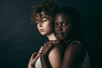 Portrait of young woman against black background