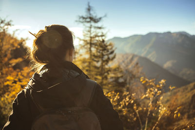 Rear view of woman standing on mountain against sky