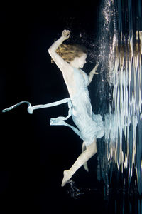 Midsection of woman dancing against black background