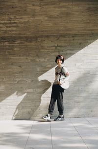 Full length of young man standing against wall