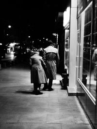 Rear view of people walking on street at night