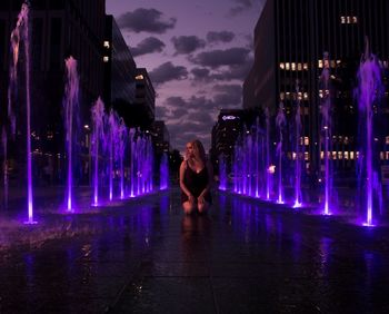 Full length of woman standing on illuminated water at night