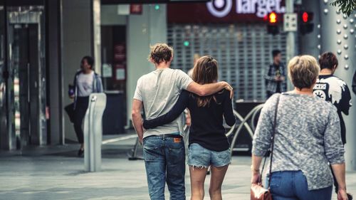 Rear view of people walking on street in city