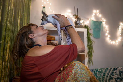 Hippie woman playing with chihuahua while sitting at home