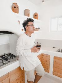 Man having drink while standing in kitchen