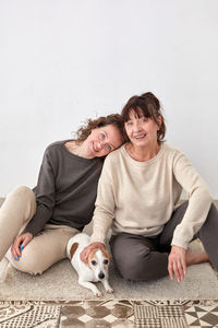 Smiling mother and daughter with dog at home