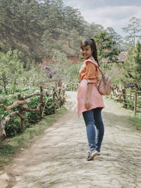 Full length portrait of a smiling young woman walking outdoors