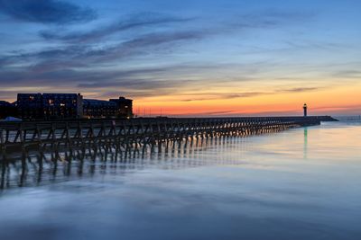 Pier over sea against sky during sunset
