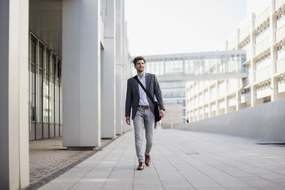 Smiling businessman with crossbody bag in the city on the move