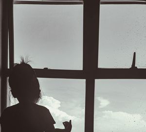 Rear view of woman looking through window