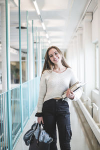 Portrait of smiling young female student in corridor of university