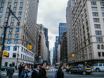 People walking on city street against buildings