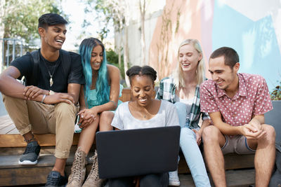 Friends using laptop while sitting on sofa at home