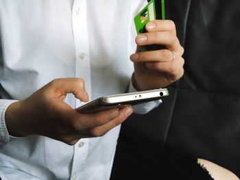 Midsection of woman making payment using credit card on mobile phone