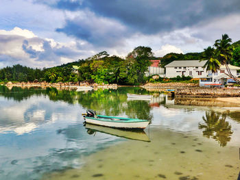 Boats in lake by buildings against sky