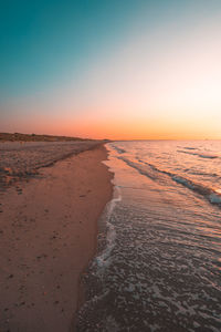 Scenic view of beach against clear sky during sunset