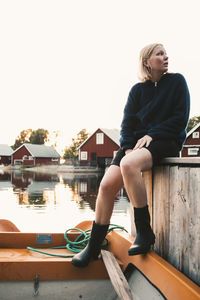 Full length of thoughtful woman sitting in boat at holiday villa against clear sky