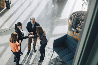 High angle view of colleagues looking at businesswomen greeting in office