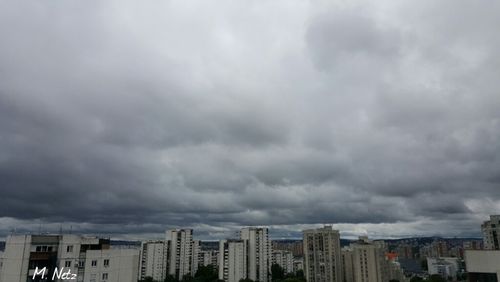 Buildings in city against cloudy sky