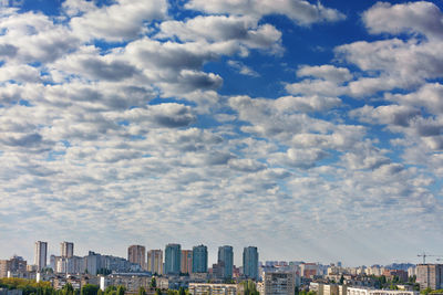 Small white-gray clouds gradually obscure the blue sky above the city.